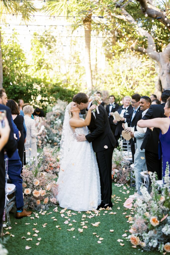 first kiss walking down the aisle at garden inspired wedding ceremony in palm beach at the colony hotel