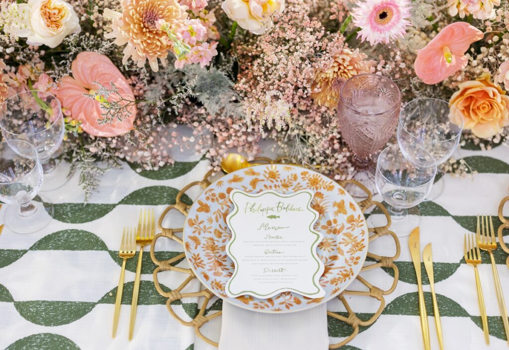 Garden inspired Palm Beach wedding reception design with coral florals, patterned green linens and rattan chargers