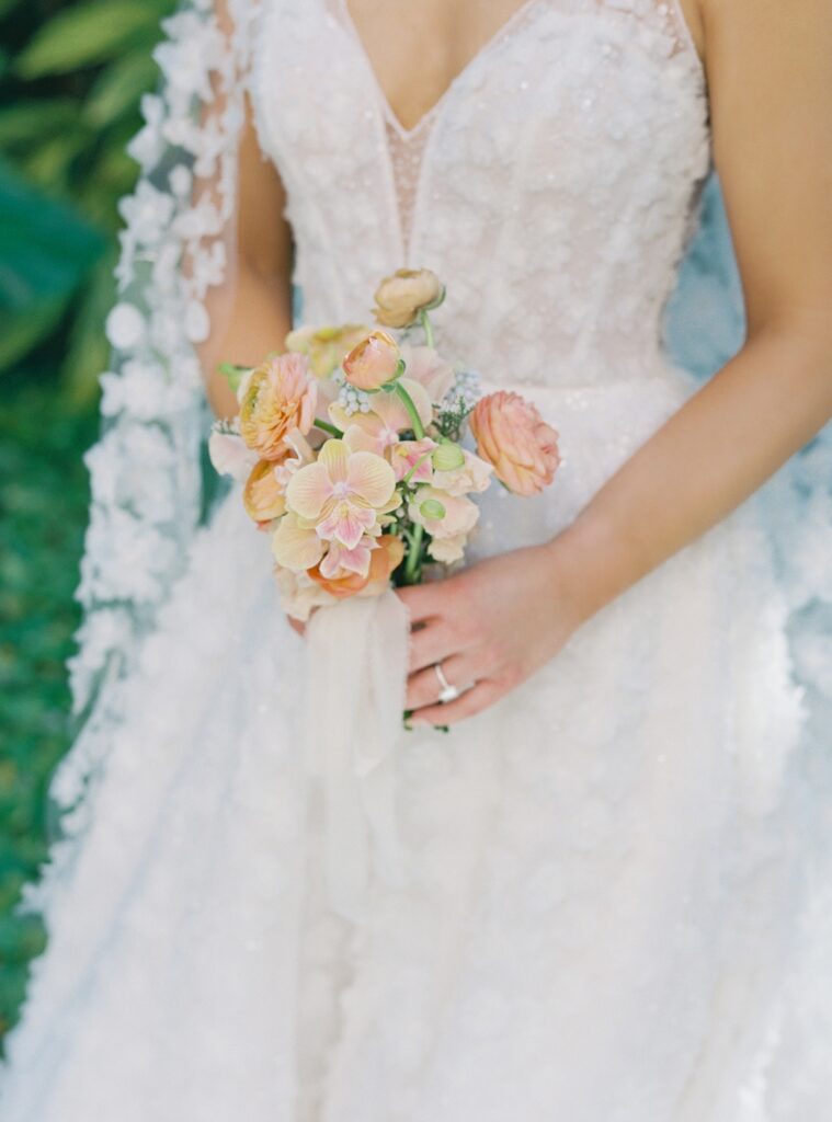 Bride holding peach ranunculus bouquet at The Colony Hotel